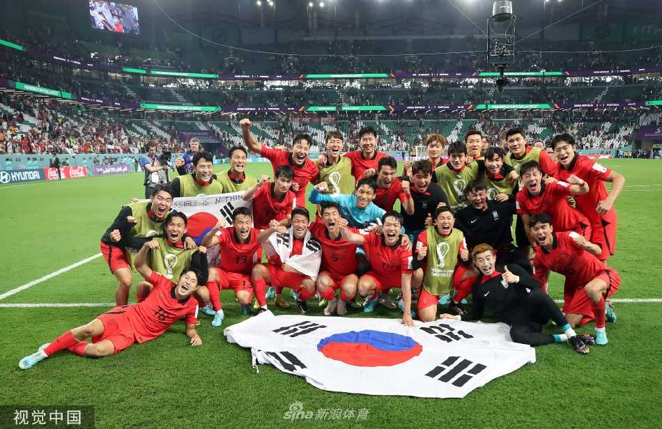 韩国球员金英权进球后与队友激动拥抱庆祝，场边替补席球员也兴奋跃起