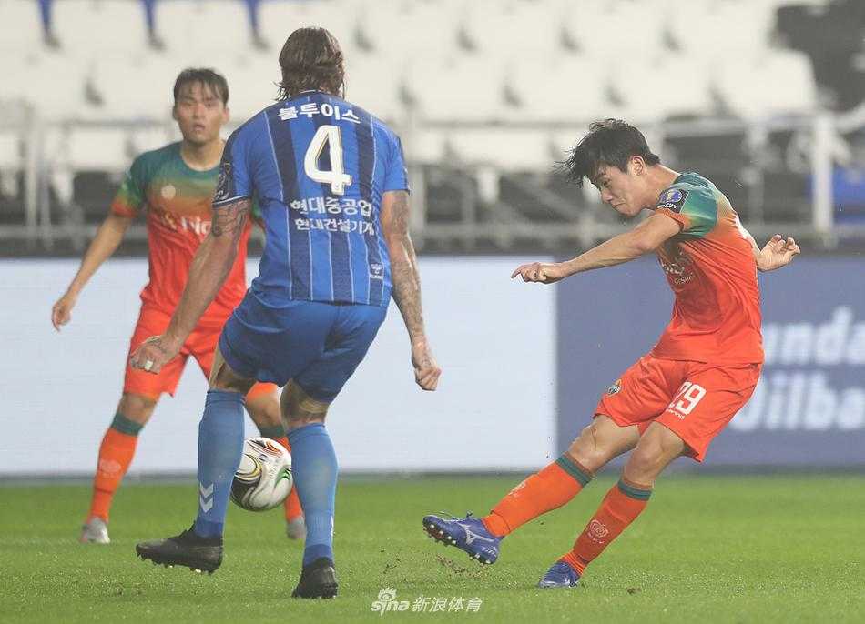 江原FC核心球员面对三人包夹防守，依旧从容不迫地护住皮球，眼神中透露出不甘与寻找出路的坚定。
