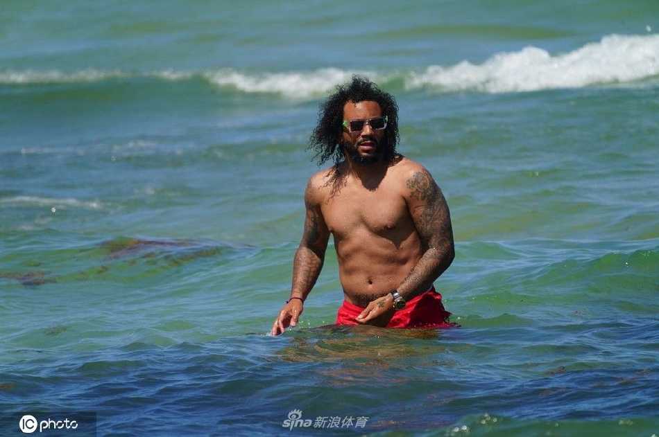 夫妻二人在湛蓝海水中嬉戏玩耍，水花飞溅中洋溢着无忧无虑的快乐与童真。