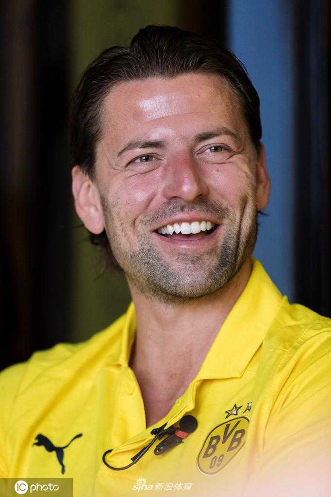 魏登费勒在广州的休息区内整理衣袖，举手投足间依然保持着职业球员的优雅气质，墙上的光影记录下这位德国传奇的东方之旅