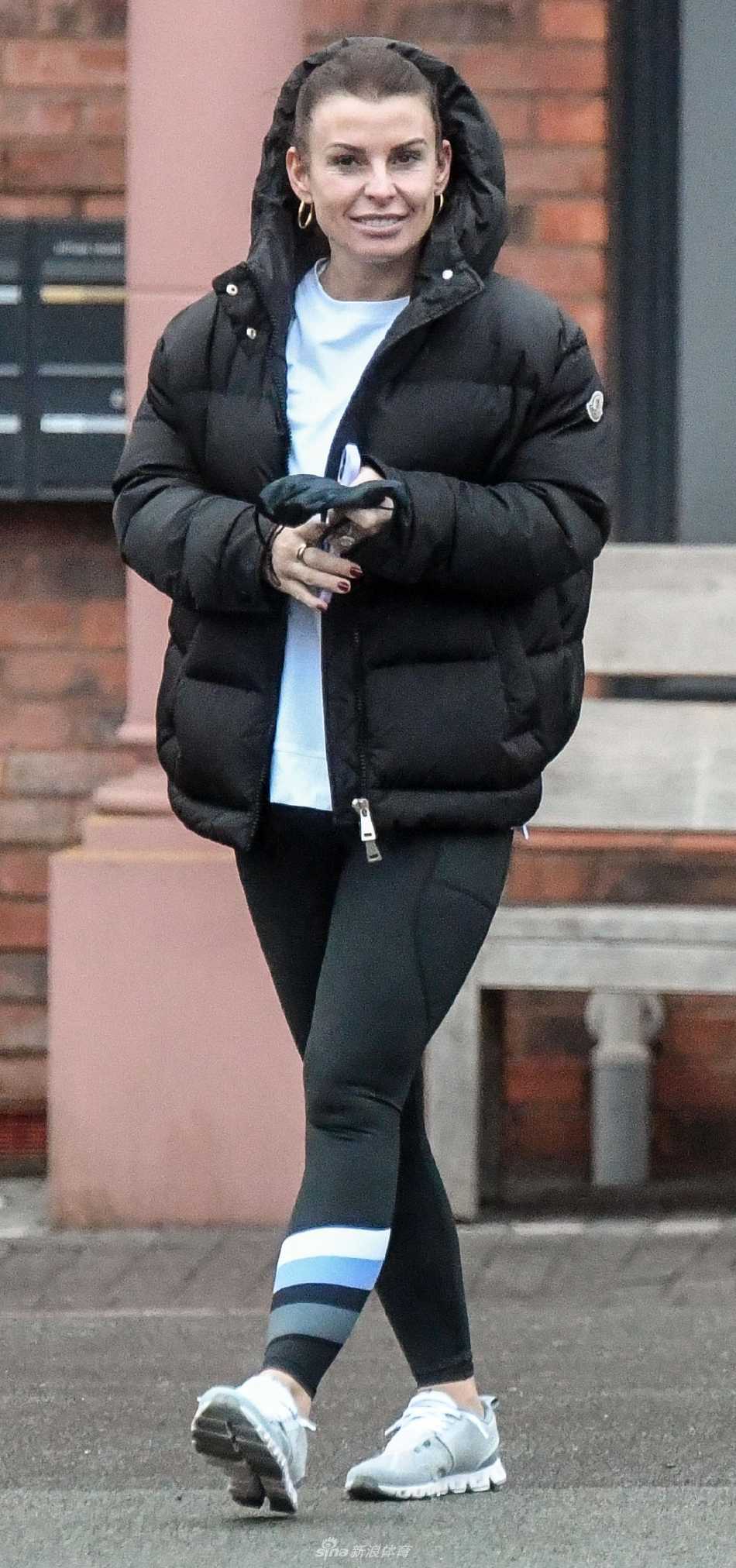 科琳·鲁尼身着米色长款大衣，手提名牌包，在柴郡街角驻足回眸，金色长发在阳光下熠熠生辉，展露优雅气质。