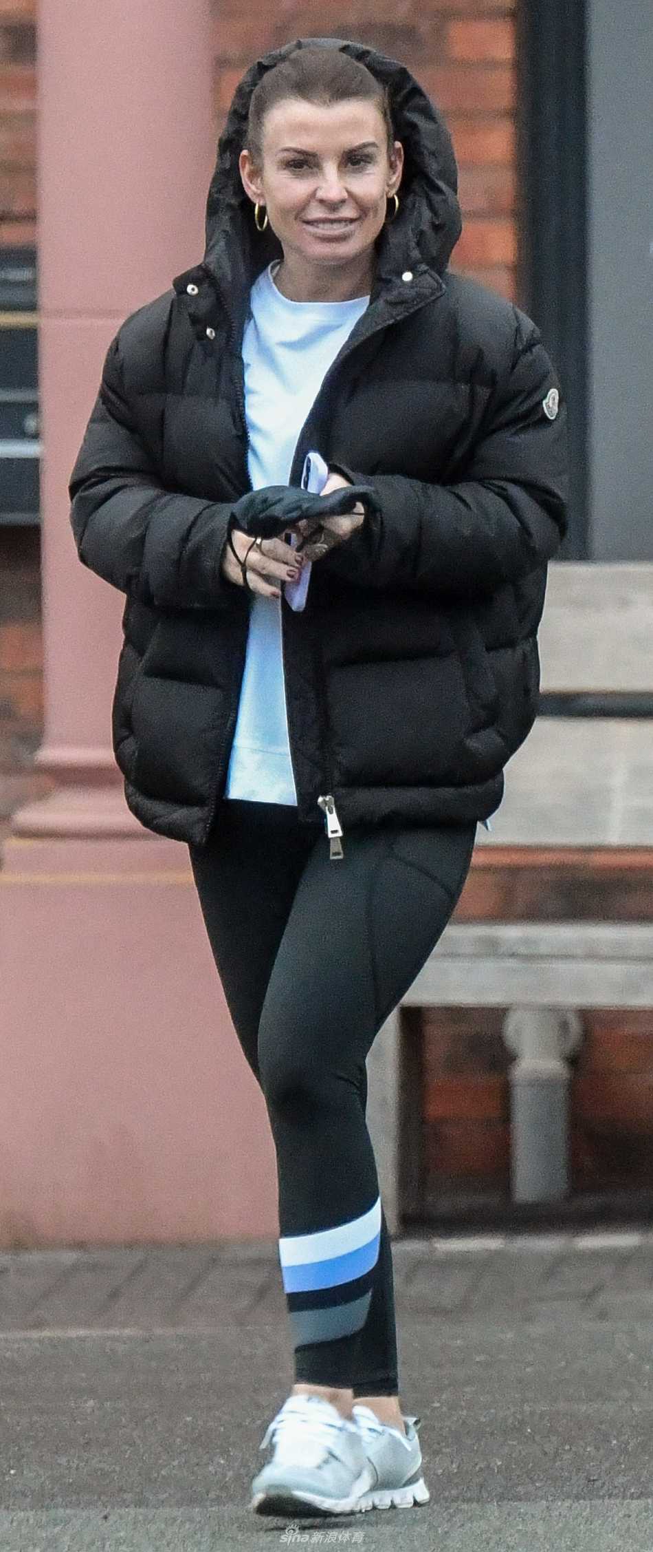 科琳一身简约时尚的装扮立于街头，双手自然下垂，笑容温暖如春，仿佛驱散了周遭所有的寒意。