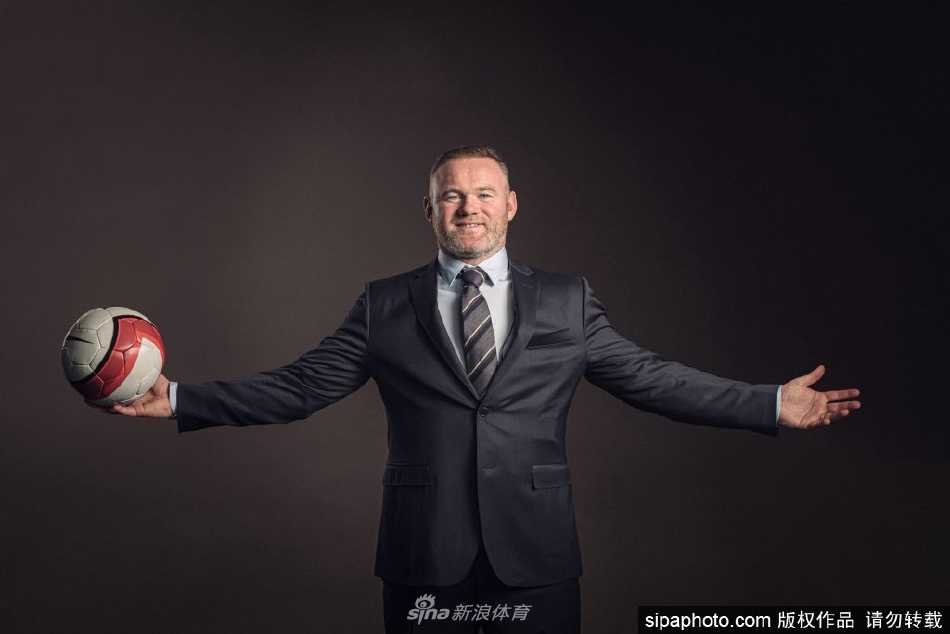 鲁尼身着华盛顿联队黑色训练服，神情专注地站在绿茵场边，手持战术板，标志性的坚毅目光中透露出对新挑战的思考与决心。
