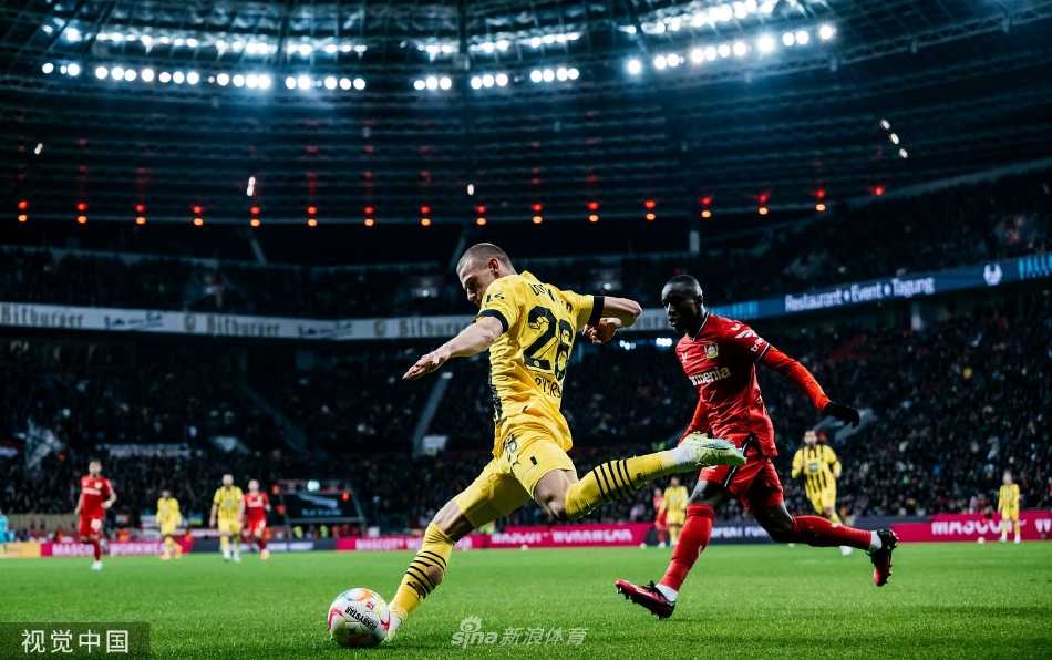 勒沃库森后卫塔普索巴在打入乌龙球后神情沮丧，他双手叉腰低头看向草地，背景中多特球员正在庆祝