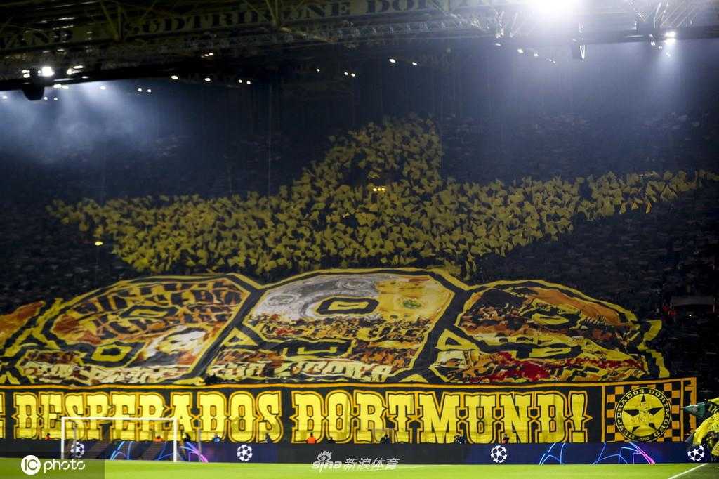 比赛进行中，球员们在场上奋力拼抢，背景是清晰可见的巨型TIFO‘1999’，它如同守护神一般见证着每一次攻防转换。