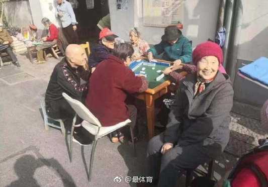天坛祈年殿前，齐达内与穿着传统服饰的中国民众合影，他双手插兜，笑容温和，背景是宏伟的古建筑。