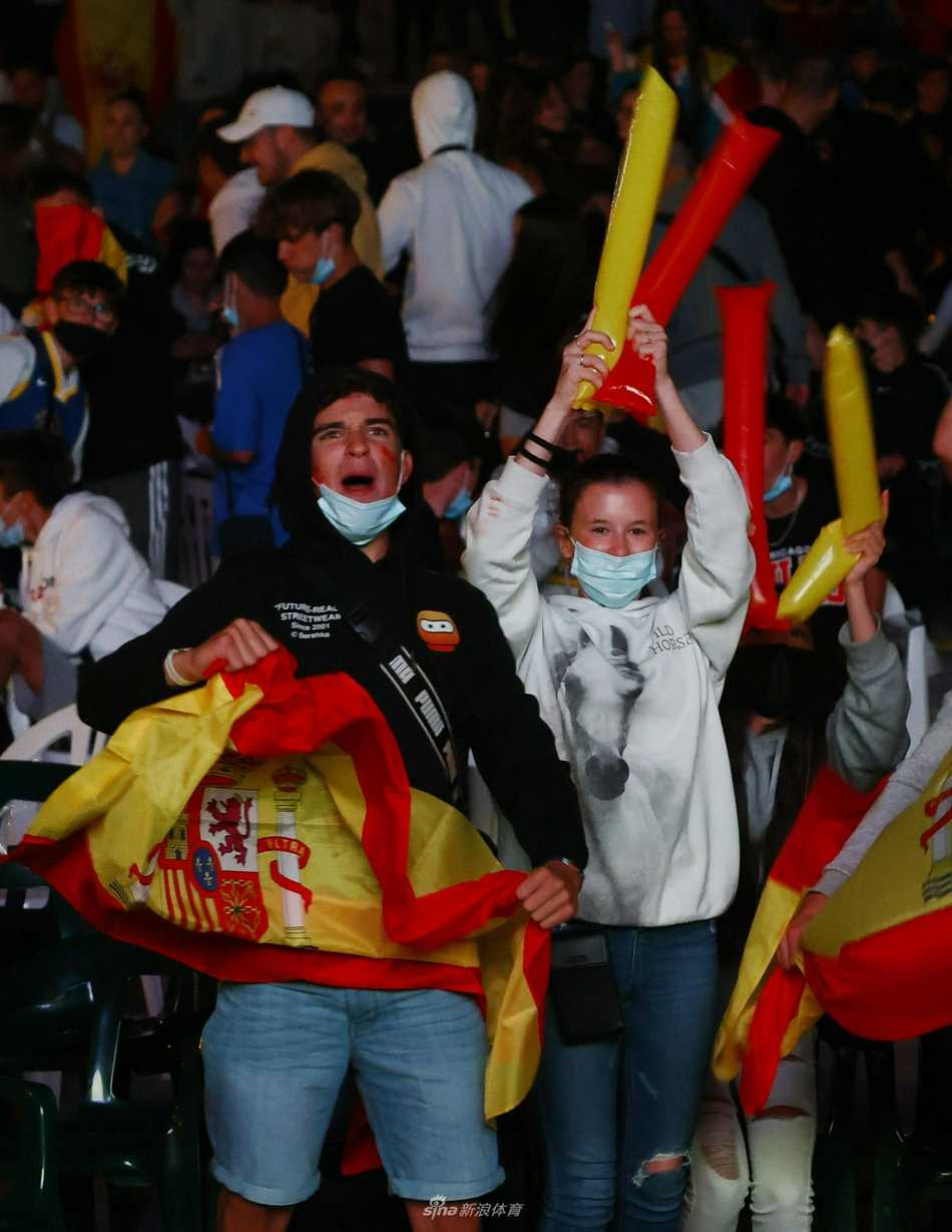 fervor en la plaza el pequeño pueblo español se arrodilla por la victoria en la semifinal de la eurocopa Vista panorámica de la plaza de Griñón al final de la noche, con los vecinos abrazados y comenzando a dispersarse lentamente, con el fondo de la pantalla aún encendida.