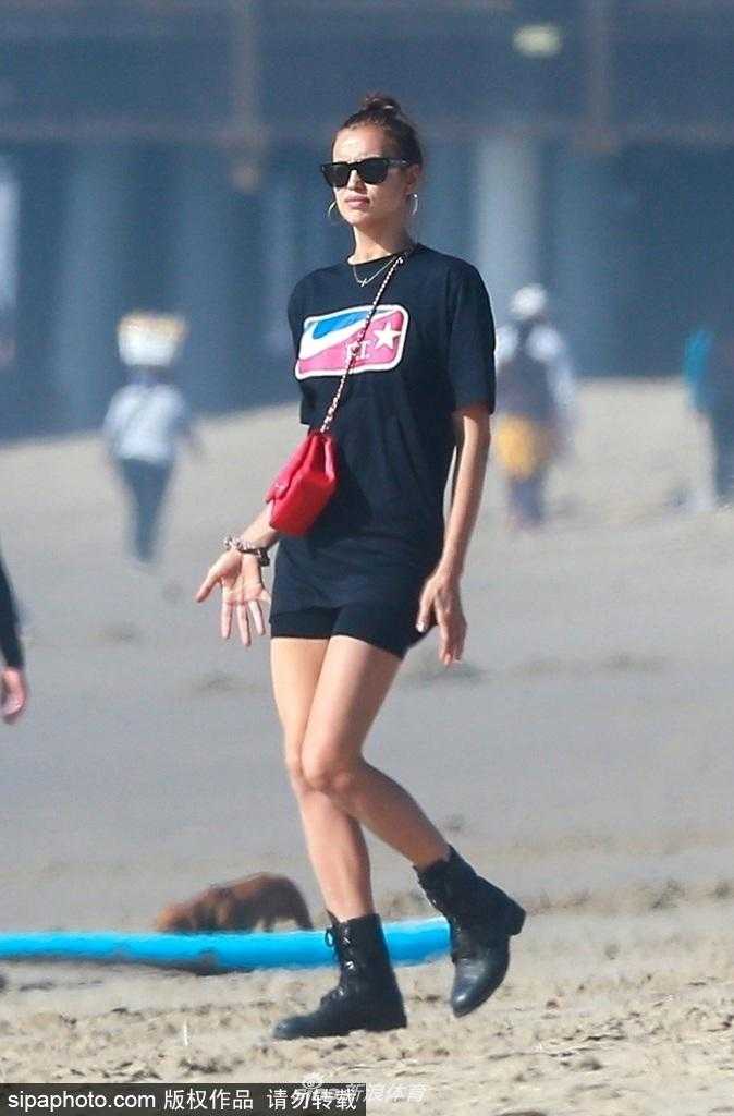 布莱德利抱着女儿在海边戏水，伊莉娜站在一旁微笑注视，海风吹拂着他们的发丝，画面唯美。