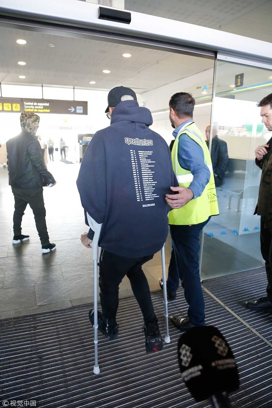 在巴塞罗那的街头，内马尔艰难地准备登上汽车，他的右脚完全不敢着地，整个人重心压在拐杖和左腿上，神情中透露出一丝焦虑。