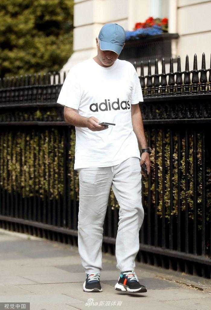 穆里尼奥在人行道上独自行走，身后是伦敦标志性的红色电话亭，神情专注而放松，仿佛在丈量着从街头到教练席的距离。