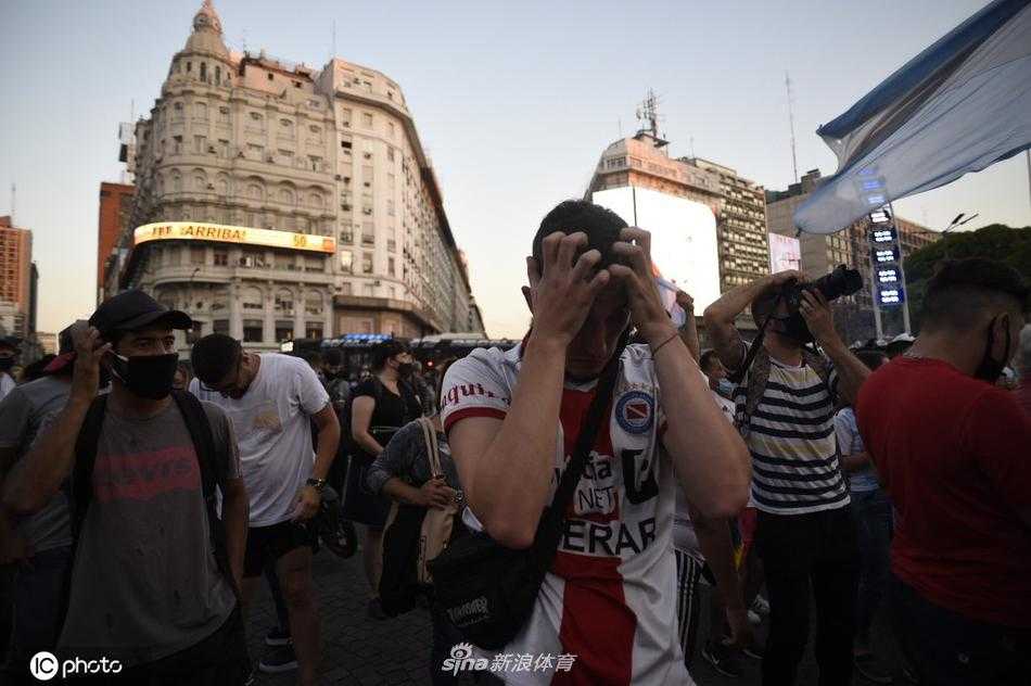 阿根廷总统府玫瑰宫外，一位头发花白的老球迷身着阿根廷10号球衣，双手颤抖地举着马拉多纳的海报，浑浊的泪水滑过满是皱纹的脸庞，眼神里是无尽的哀伤与不舍。