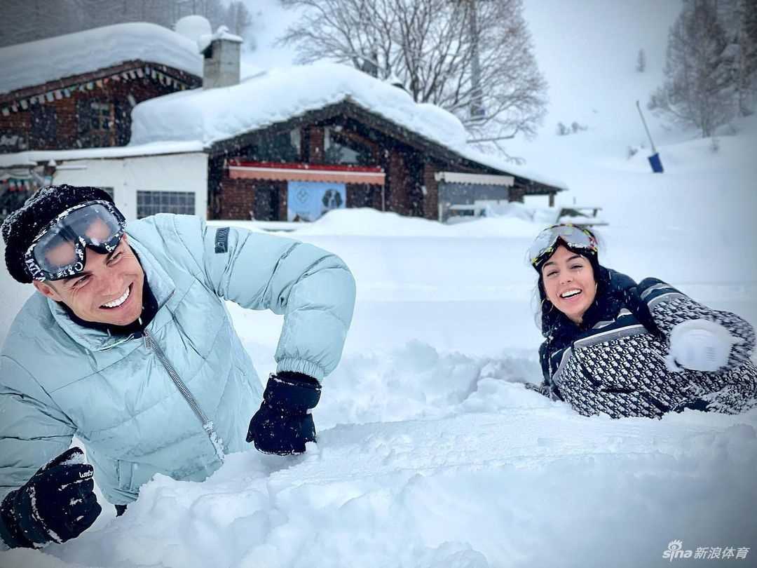 乔治娜独自站在雪地中，一身时尚的皮草搭配紧身裤，展现出她作为时尚辣妈的独特魅力。她面带微笑，自信地面对镜头，身后是连绵的雪山和清澈的蓝天，整个画面既有时尚大片的质感，又充满了冬日度假的闲适感。
