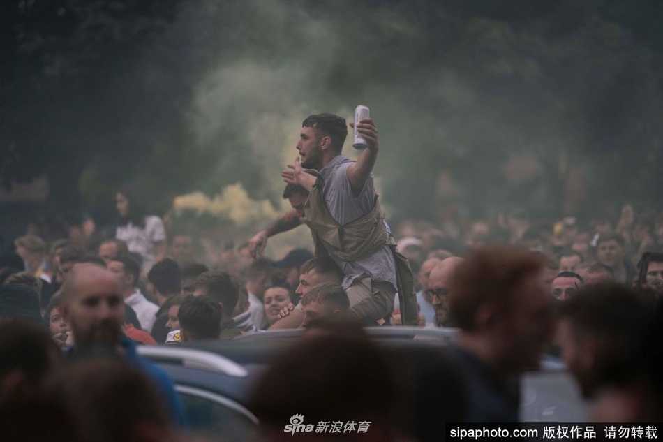 在漫天的白色纸屑雨中，一位利兹联球迷高高举起手中的烟火棒，橘红色的光芒划破夜空，映照出他脸上那份近乎癫狂的喜悦，仿佛要将十六年的等待在这一刻全部燃烧殆尽。