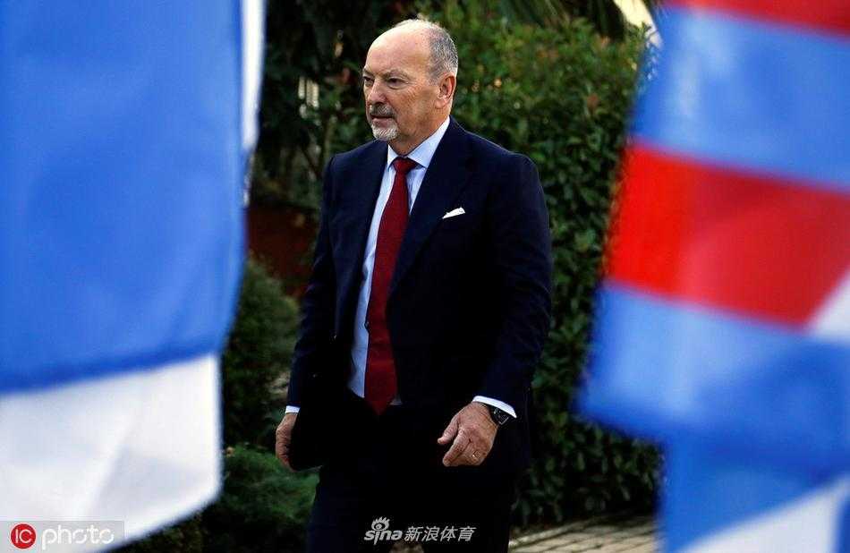 镜头捕捉到摩尔独自站在峰会会场的巨大利物浦队徽背景板前，双手交叉于身前，神情庄重而深邃，仿佛在思考如何引领这支冠军之师迈向新的辉煌