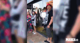 动态画面中，一位利物浦球迷兴奋地跳跃着，双手高高举起一个用银色气球精心扎成的欧冠奖杯形状的气球，气球在阳光下闪闪发光，周围的朋友们纷纷鼓掌欢呼，仿佛真的在举起真实的奖杯