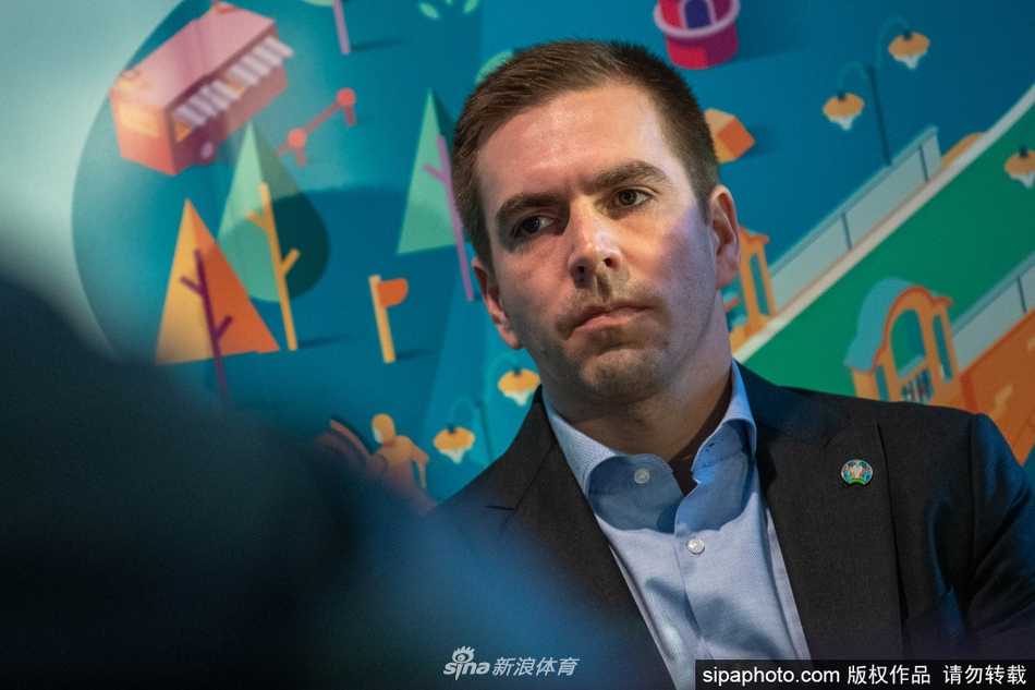 身着深色西装的拉姆在新闻发布厅内目光坚毅，仿佛正以总监的视角审视着欧洲杯的宏伟蓝图，嘴角带着一丝从容的微笑。