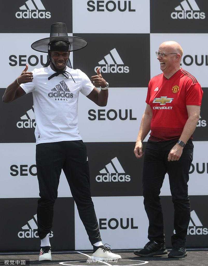 博格巴戴着时尚墨镜，从容步出首尔机场到达厅，扑面而来的韩流粉丝热情让这位法国巨星露出略带羞涩的微笑。