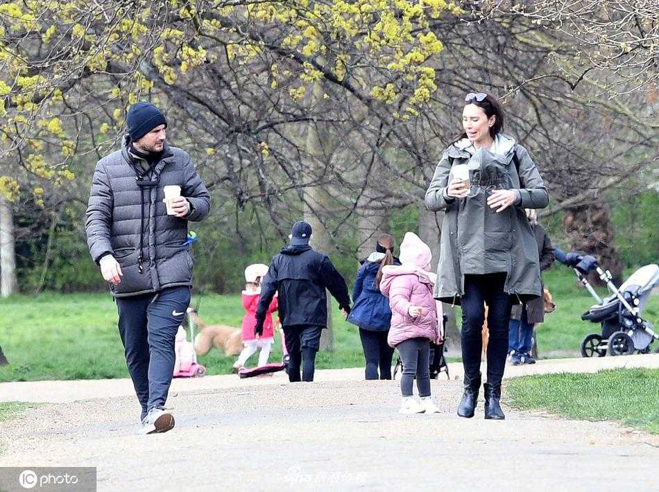 兰帕德夫妇并肩走在洒满阳光的林荫道上，两人轻松地聊着天，身后的公园景色宁静优美，预示着他人生新篇章的开启。