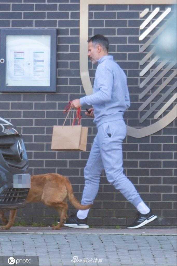 吉格斯蹲下身子轻轻抚摸爱犬的头部，棒球帽的阴影遮住了他的眼睛，但嘴角那一抹上扬的弧度清晰可见，这一刻他不再是传奇，只是一个享受生活的爱犬人士。