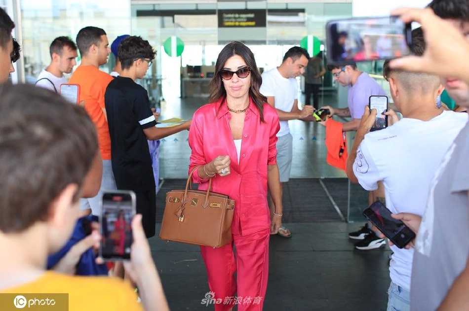 哈维与妻子努莉亚面对镜头露出微笑，努莉亚亲密地靠在哈维身边，背景是机场的灯光，整个画面充满温暖幸福的氛围。