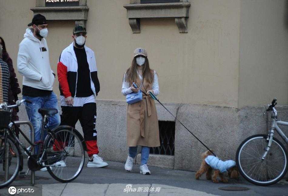 在散步途中，唐纳鲁马似乎被街边的什么吸引了注意力，他伸出手臂指向某个方向，侧身对女友说着什么，仿佛在分享一个有趣的发现，而阿莱西娅则顺着他手指的方向望去，脸上带着好奇的微笑。
