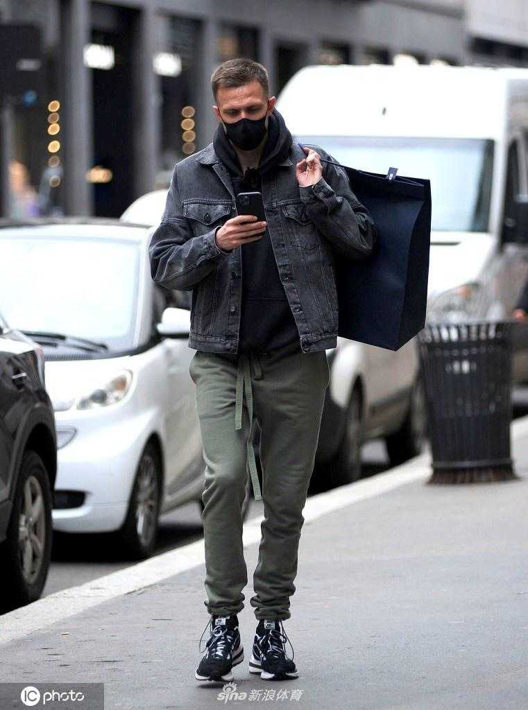 伊利契奇在米兰街头漫步，他身穿深色长款大衣，搭配休闲裤，肩挎背包，神情轻松，展现出一位成熟型男的时尚品味。