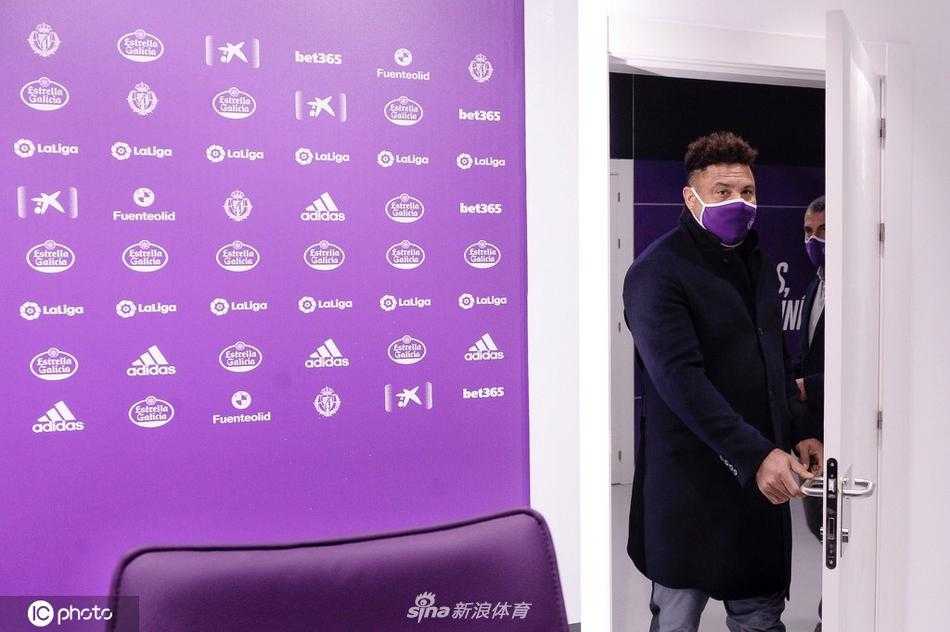 发布会现场的近景镜头里，罗纳尔多微微侧身，似乎在认真倾听记者的提问。他的面部轮廓相比球员时代圆润了不少，但眉宇间依旧透着一股不服输的倔强。桌面上摆放着的矿泉水瓶和麦克风，记录着这位传奇巨星转型商人的真实瞬间。