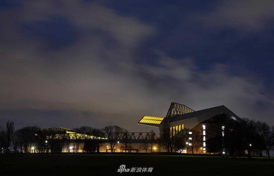 夜幕下的安菲尔德路看台，巨大的广告牌灯光照亮了空无一人的街道，却仿佛能让人透过这寂静的画面，听到未来某天这里将会响起的、为冠军而战的震天欢呼与歌唱。
