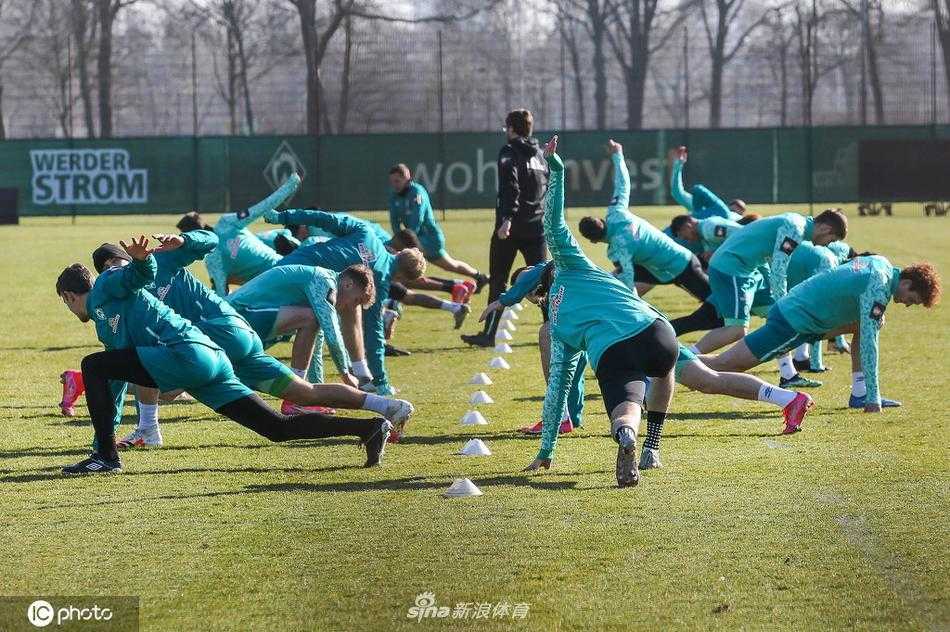 训练场一侧，教练组正对着战术板向球员们讲解跑位路线，球员们认真聆听