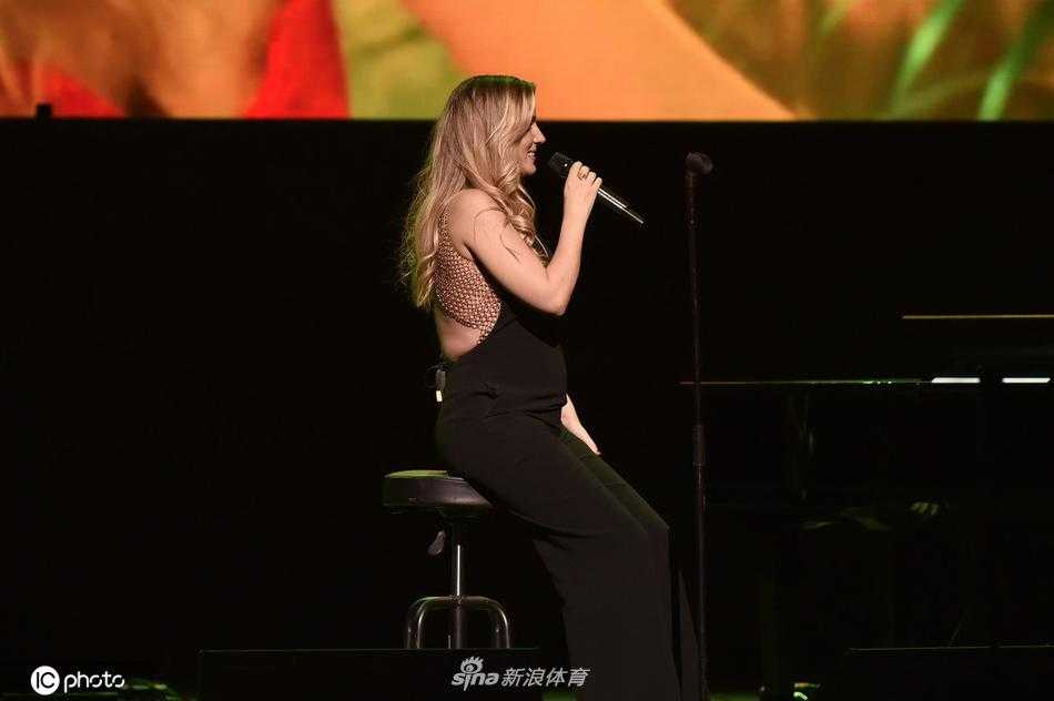 特写镜头捕捉到埃杜尔尼演唱时动人的表情，她眉头微蹙，情感充沛，嘴唇几乎贴着麦克风，仿佛在向腹中的宝宝倾诉着最温柔的摇篮曲。
