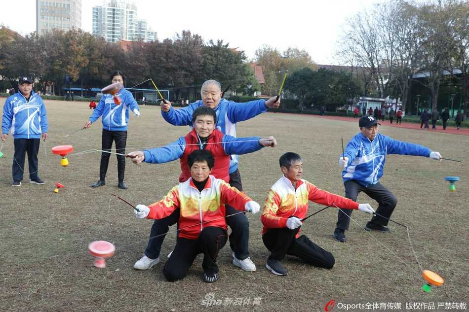 几位队员站成一排，同时进行空竹表演，他们的动作整齐划一，空竹在空中旋转的轨迹交错纵横，仿佛在共同演奏一曲无声的交响乐，充分展现了团队的默契与空竹运动的集体之美。