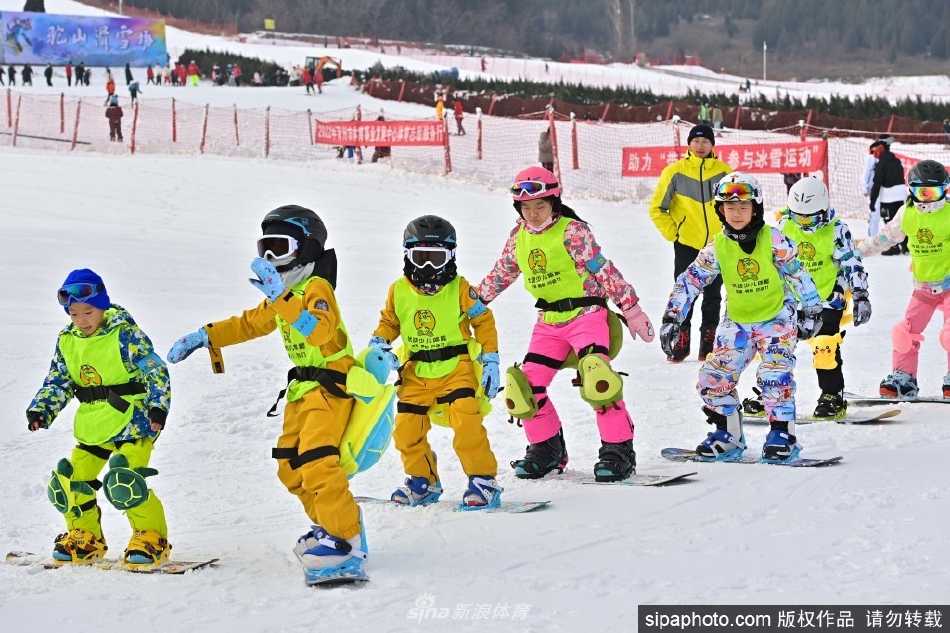 滑雪新手在教练指导下于初级雪道上小心翼翼地练习滑行，脸上洋溢着既紧张又兴奋的笑容。