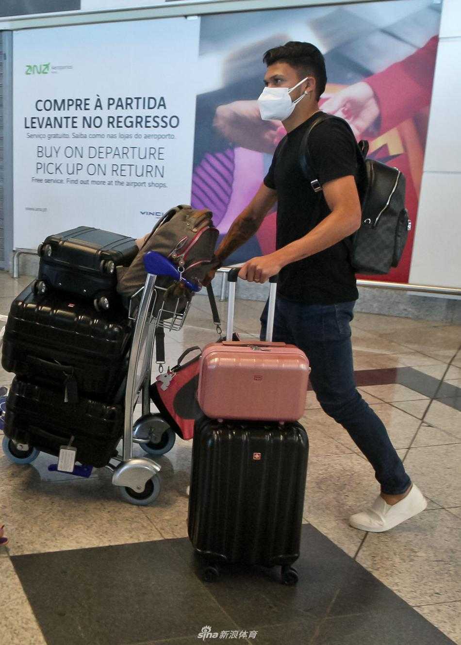 埃文尼尔森正面大步走来，白色的T恤在阳光下反着光，他整个人的轮廓被光线勾勒得充满活力。身后的围墙和树木虚化成背景，凸显出他作为球队未来锋线希望的核心地位，归队的脚步坚定有力。