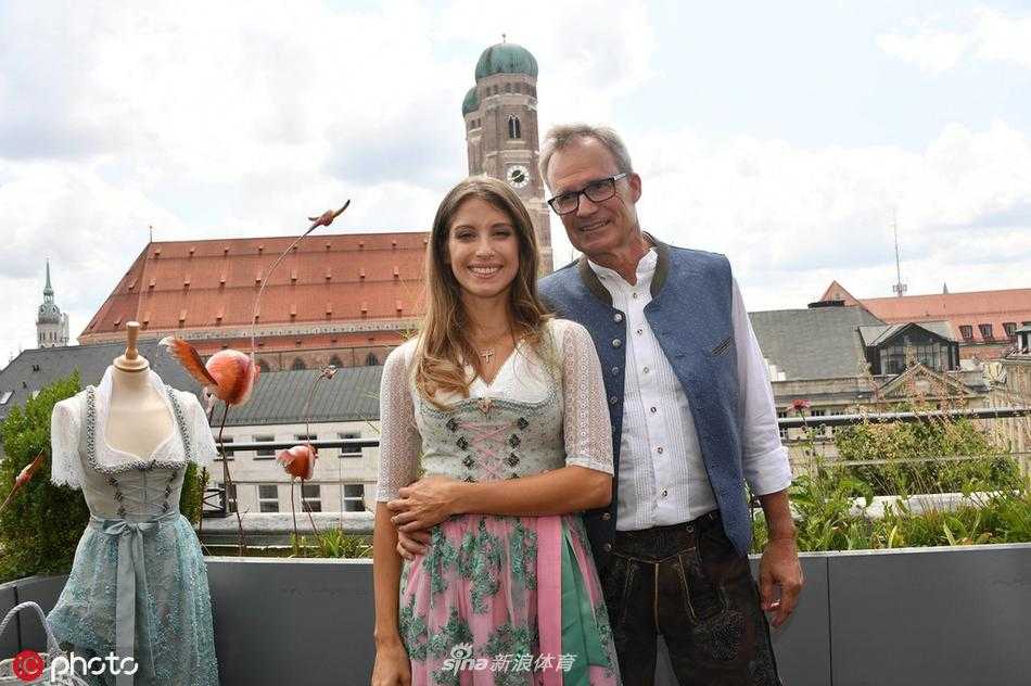 凯茜与模特们一同亮相，她身着一袭深邃的蓝色Dirndl，显得高贵典雅。众人站成一排，裙摆随风轻扬，仿佛在向世界发出邀请，共赴一场巴伐利亚的时尚庆典。