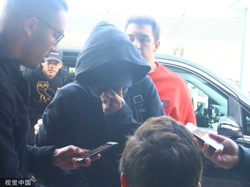 人群的包围与内马尔的独行形成鲜明对比，他低着头，目光专注在前方的道路上，仿佛周围的喧嚣都与他无关，只想尽快穿过这片‘是非之地’。
