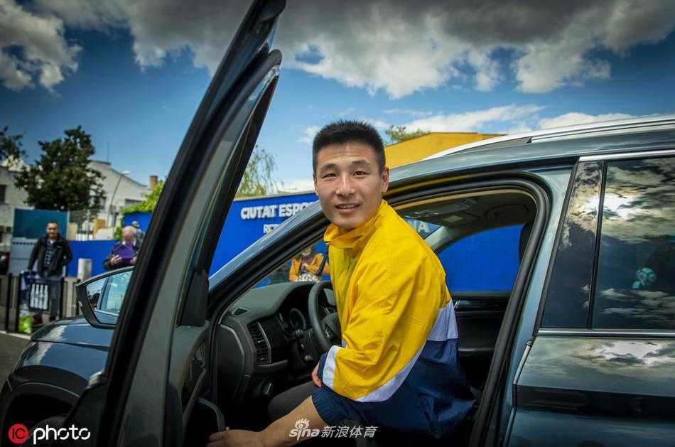 武磊身着一件休闲的灰色T恤，在西班牙人俱乐部门外的路边停下脚步。他微微弯腰，脸上带着温和而谦逊的笑容，正专注地为一位身穿西班牙人队球衣的小球迷在签名本上写下自己的名字，小球迷则仰着头，眼睛里闪烁着崇拜的光芒。