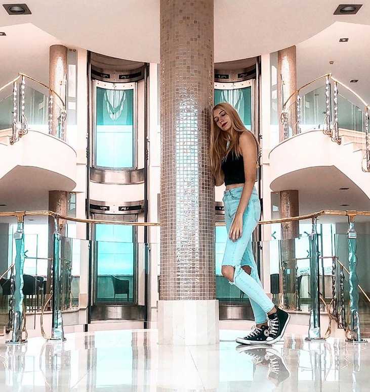 乔治娜身穿明亮的黄色毛衣，在阳光下笑容灿烂，充满活力的形象与巴塞罗那这座热情的城市相得益彰