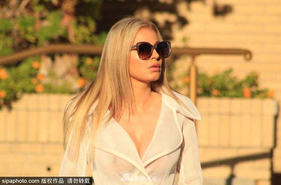 安娜手持浅色手包，侧身而立，透视裙摆下健康的小麦色肌肤在阳光下泛着光泽，精致的妆容与简约的配饰相得益彰，展现出巴西女郎独有的自信与不羁。