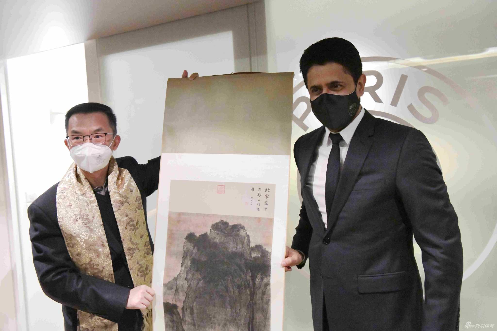 巴黎圣日耳曼俱乐部主席纳赛尔（左）将一件印有‘郎朗’和10号号码的球队专属球衣，赠送给钢琴家郎朗（右），郎朗手持球衣，笑容满面。