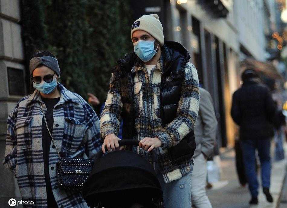 在米兰的街头一角，恰尔汗奥卢蹲下身子，耐心地为孩子整理衣物，他的妻子辛雅娜安静地站在一旁，一家三口简约的穿搭与身后欧式建筑的典雅背景融为一体，透露出生活的平静与幸福。