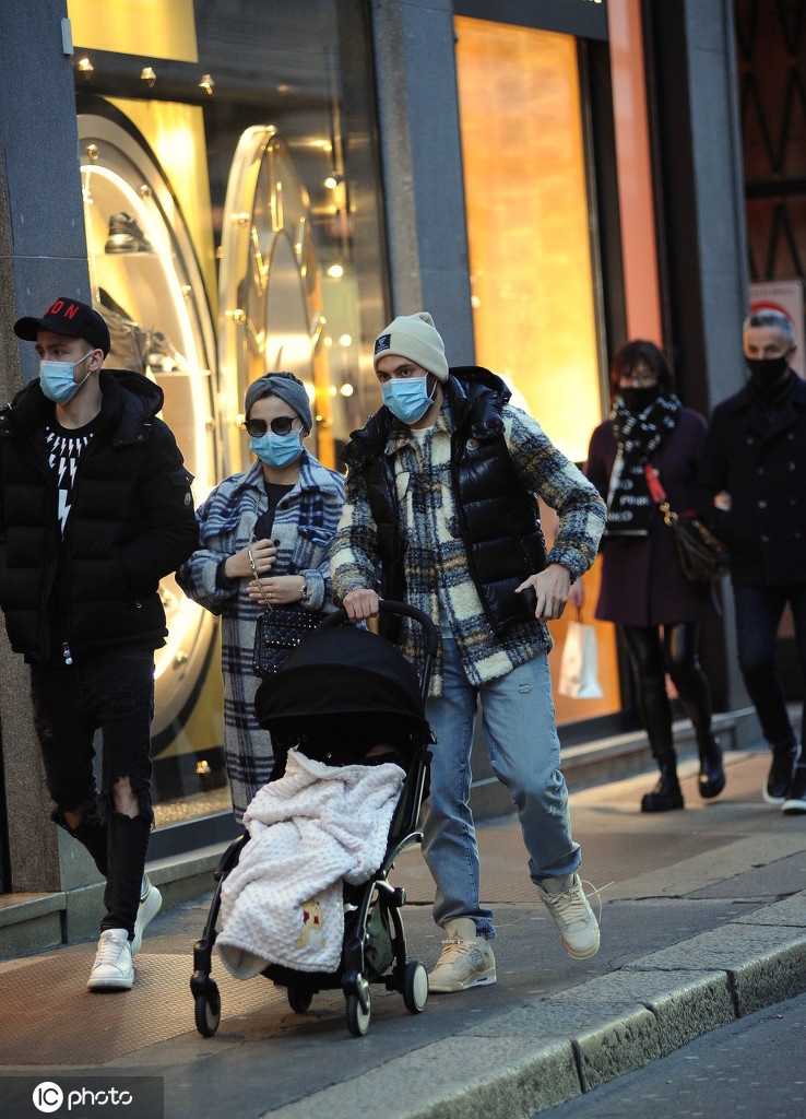 画面中，恰尔汗奥卢将孩子轻轻抱起，让孩子的小手触摸路边一棵大树的树干，他的妻子则在一旁温柔地注视着这对父子，冬日的暖阳透过树枝洒在他们身上，画面如同电影场景般美好。
