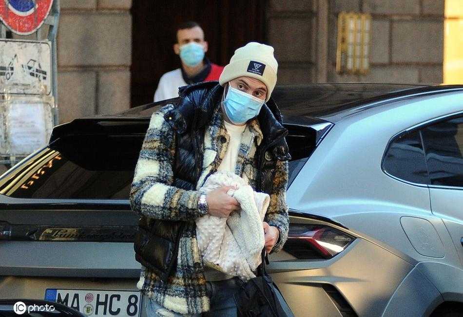 午后阳光柔和，恰尔汗奥卢一家三口走在米兰的一条石板路上，父亲推着婴儿车，母亲挽着父亲的手臂，孩子在车里安然入睡，构成了一幅岁月静好的家庭散步图。