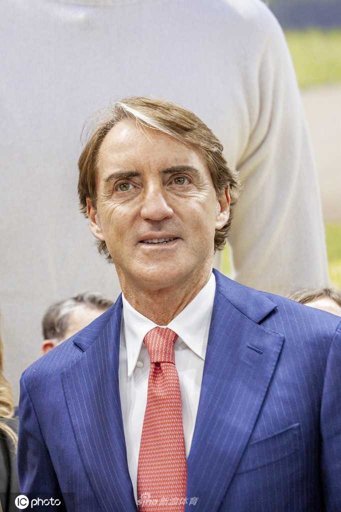 曼奇尼俯身与手持意大利国旗的小球迷亲切交谈，展现冠军教头的温柔一面