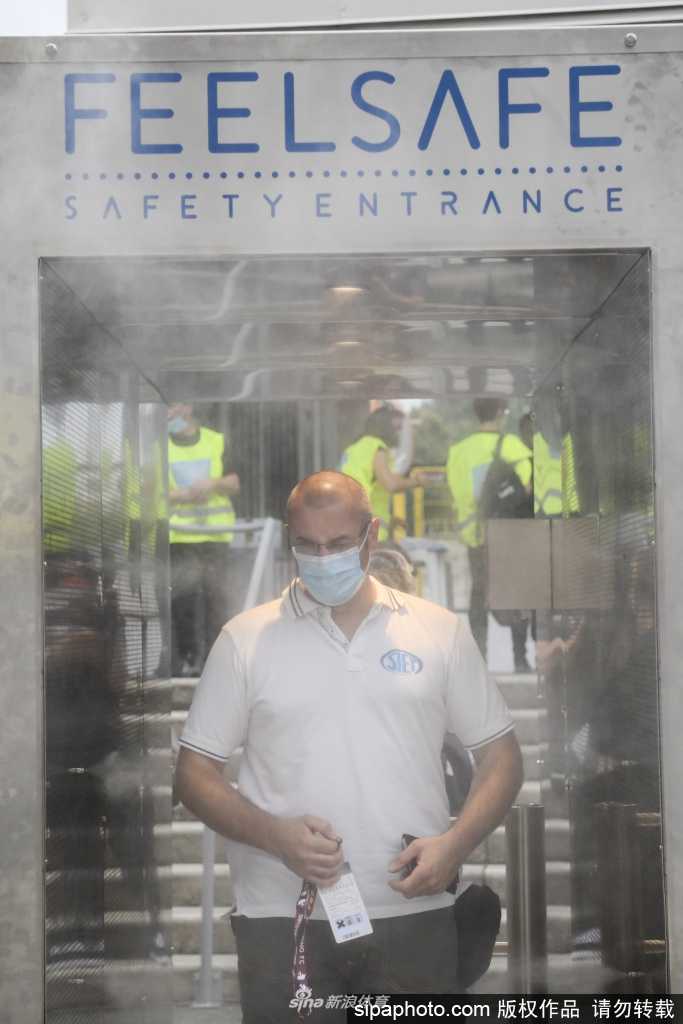 一名都灵当地记者正准备进入球场工作，他身后就是正在运行中的‘Feel Safe’系统。这张特写清晰地展示了系统的操作界面，绿色的指示灯亮起，仿佛在无声地宣告检测通过，令人安心。