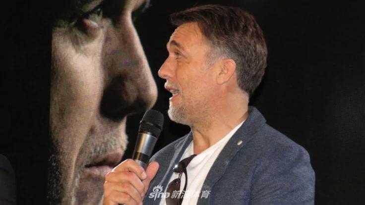 巴蒂斯图塔身着一袭深色休闲装，双手插兜，嘴角带着一抹淡然的笑意。这份从容，是岁月赋予一位传奇射手最好的礼物。他身后的背景板，仿佛是他辉煌历史的缩影。