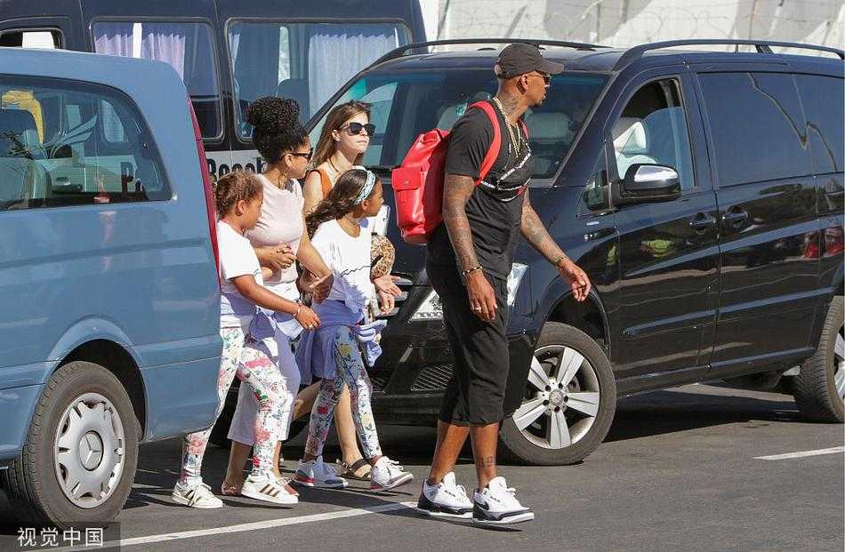 博阿滕和一位家人并肩走在海滨小道上，他侧身看向镜头，墨镜中倒映出地中海的波光，画面充满了夏日度假的闲适感