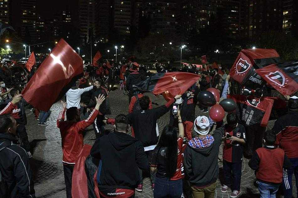 几名年轻的纽维尔老男孩球迷挤在车窗边，他们稚嫩的脸庞被涂上红黑油彩，双手紧握着自制的标语牌，上面写满了对偶像的深情告白。对于这些孩子来说，梅西不仅是遥不可及的球王，更是他们身边那个从同样街道走出去的大哥哥。