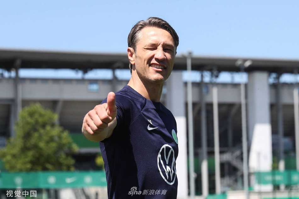 主教练尼科·科瓦奇正在训练场边全神贯注地指导球员，手拿战术板，神情认真而坚定。