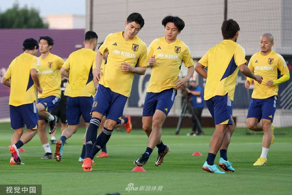日本队球员在卡塔尔阳光下进行热身训练，蓝色训练服在绿茵场上格外醒目