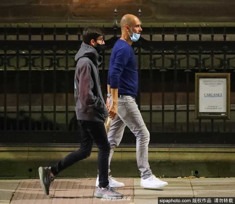 年轻的马里乌斯穿着休闲运动装，双手紧紧环抱住父亲瓜迪奥拉的腰，眉头紧锁，用尽全力将父亲往后拖拽，展现出保护者的姿态，而瓜迪奥拉则身体前倾，目光仍锁定在挑衅者的方向。